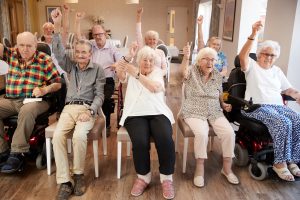 Group of happy older adults sitting together at a senior living program's class.